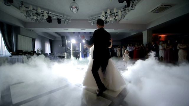 新娘在婚礼上跳舞。以白光突出的浓烟。婚礼上新婚夫妇的第一支舞。视频素材