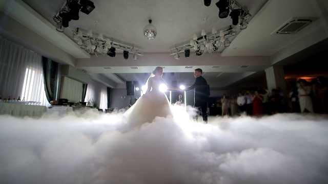 新娘在婚礼上跳舞。以白光突出的浓烟。婚礼上新婚夫妇的第一支舞。视频素材