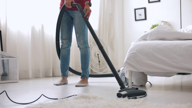 特写女人用吸尘器清洁地毯，打扫房间视频素材
