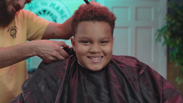 一个小男孩在剪头发时对着相机微笑的肖像视频下载
