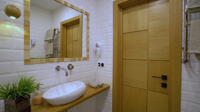现代化的浴室内部，白色的洗脸盆和墙上的镜子，酒店服务视频素材
