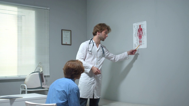 医生向男孩展示人体图片并解释一些事情视频素材