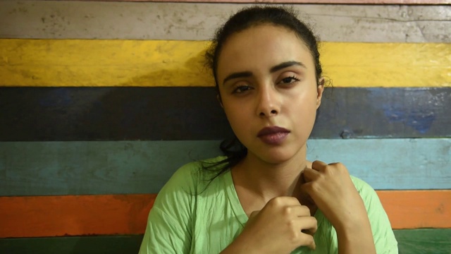 年轻美丽的中东女孩穿着绿色t恤，表情严肃。视频下载