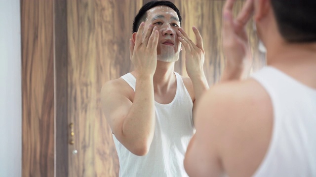 一个年轻的亚洲人在浴室里用口罩视频下载