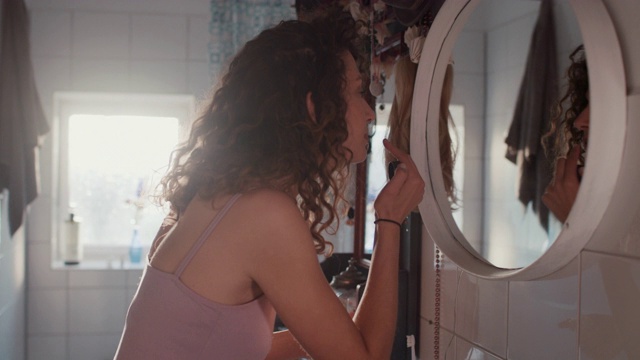 年轻女子在浴室镜子前化妆视频下载