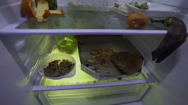 在冰箱里找食物的人。男人的手在冰箱里挖洞，试着吃剩菜，然后合上。视频下载