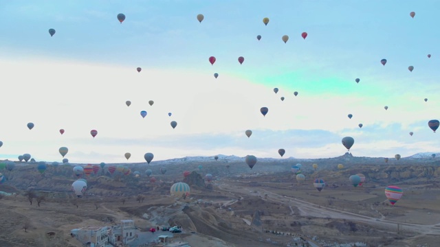 在土耳其卡帕多西亚，日出时湛蓝的天空中有许多热气球的空中山谷景观视频素材