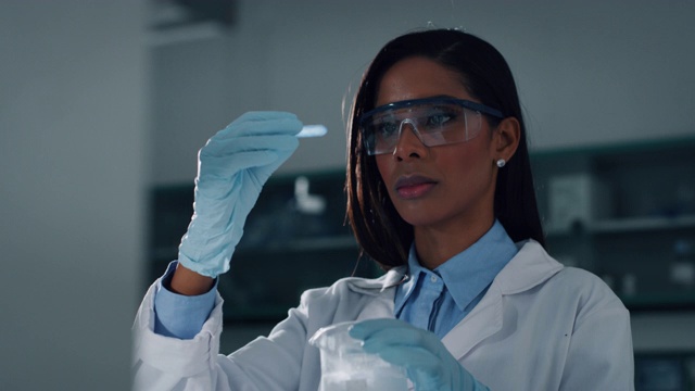 一位深色皮肤的女科学家正在实验室的试管中分析提取DNA和分子的液体视频素材