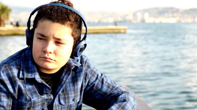 一个心烦意乱的小男孩独自坐在海边视频下载
