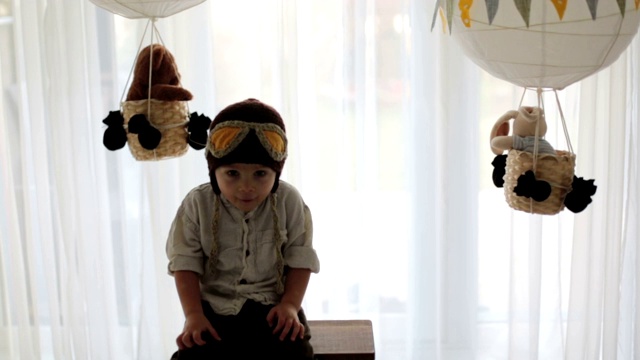 可爱的蹒跚学步的男孩，玩飞机和泰迪熊，气球和身后的玩具视频素材