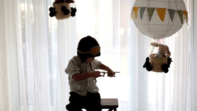 可爱的蹒跚学步的男孩，玩飞机和泰迪熊，气球和身后的玩具视频素材