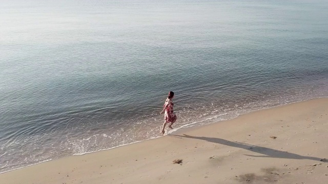 女人在海滩上跑步的鸟瞰图视频素材