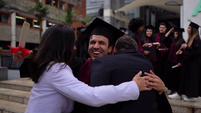 激动的年轻人跑向父母拥抱他们后，收到了他的大学文凭，所有的微笑视频下载