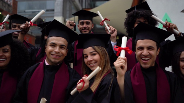 一群快乐的学生拿着他们的大学文凭面对镜头，露齿微笑视频素材