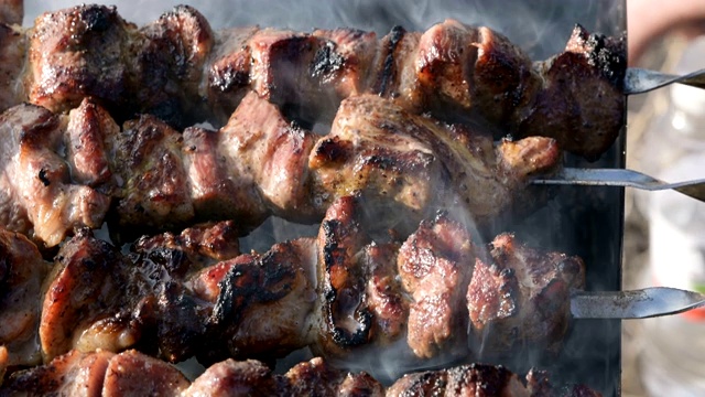 在一个阳光明媚的日子里，美味的肉片串在烧烤室外油炸。多汁的烤肉盘视频素材