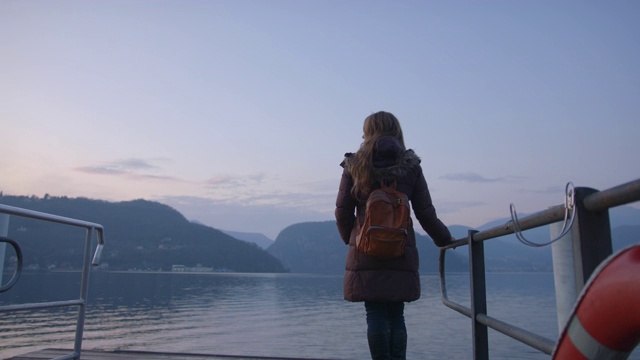 一个女人站在码头上望着宁静的湖面视频素材
