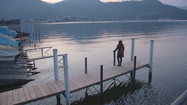 一个女人站在码头上望着宁静的湖面视频素材