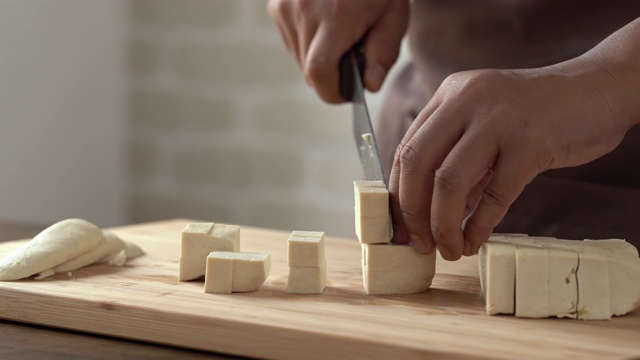 特写厨师的手切片和切豆腐与刀在木制砧板厨房准备烹饪配料视频下载