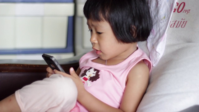 亚洲小女孩在家里使用智能手机视频素材