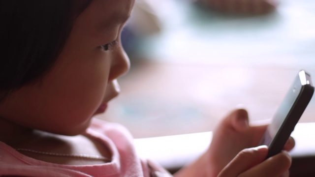 亚洲小女孩在家里使用智能手机视频素材