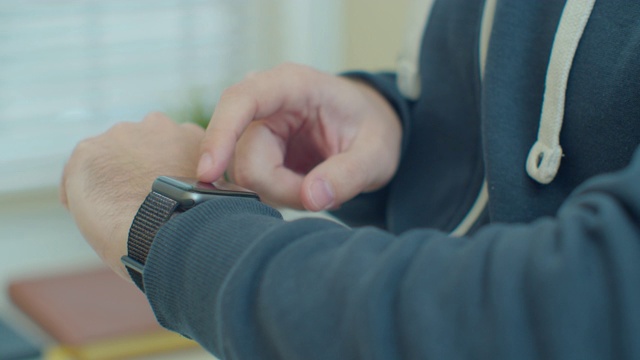 男性手上的智能手表。男人在窗边用智能手表。手腕的近景与智能手表。视频素材