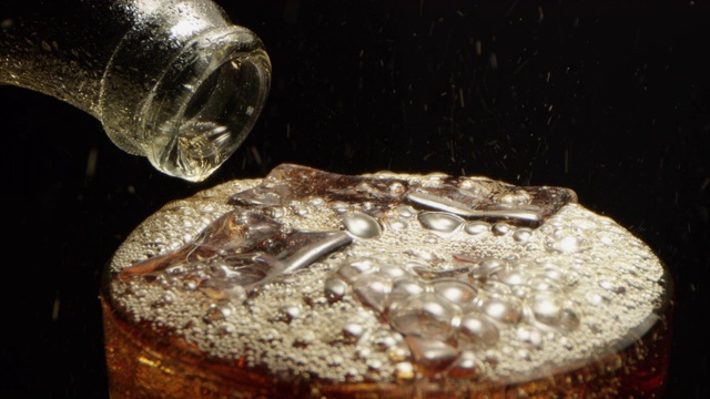可乐倒进一个有冰块的玻璃杯，微距拍摄红与黑的背景视频素材