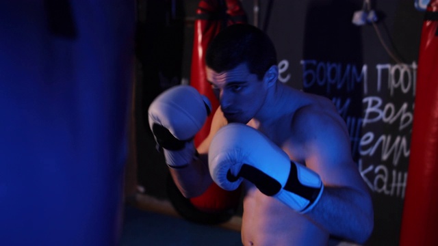 年轻男子拳击手在体育馆练习沙袋视频下载