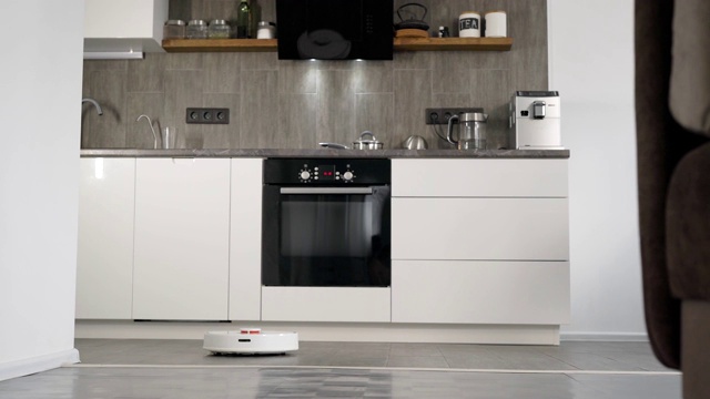 在一个时尚现代的厨房里正在打扫。自动吸尘器机器人沿着它的轨迹移动。智能家居的元素让人们的生活更轻松视频素材