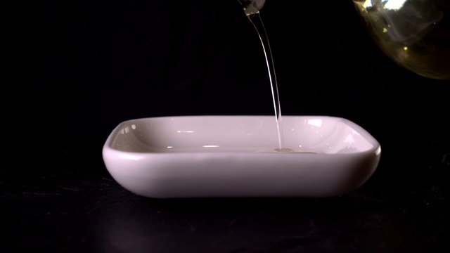 橄榄油倒在一个黑色背景的特写视频素材