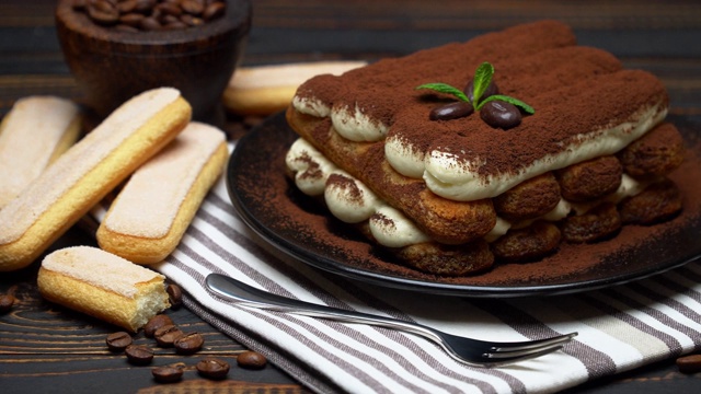 经典的提拉米苏甜点和savoiardi饼干在陶瓷盘子上的木制背景视频下载