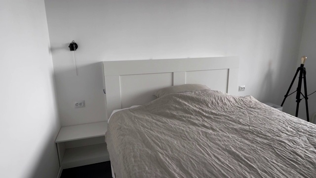 现代卧室的内部一个明亮的房间，白色的墙壁，一张宽大的床，一条毯子和一个枕头视频素材