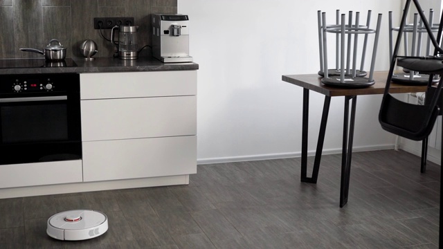 在一个时尚现代的厨房里正在打扫。自动吸尘器机器人沿着它的轨迹移动。智能家居的元素让人们的生活更轻松视频素材