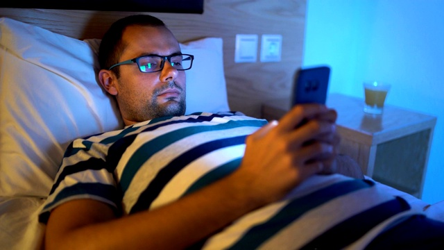 一个拿着手机睡觉的男人视频素材