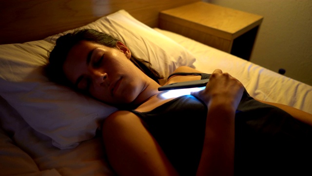 拿着手机睡觉的女人视频素材