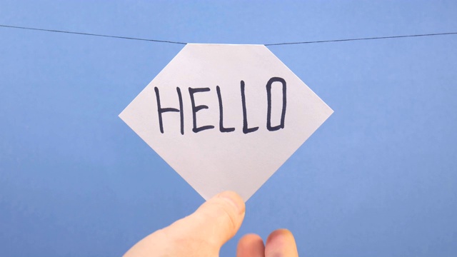 一名男子在蓝色背景上挂了一张白纸，上面写着黑色的“你好”字样视频下载