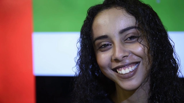 近距离的年轻美丽的女孩与黑色的头发，站在阿拉伯联合酋长国的国旗视频下载