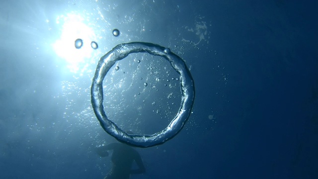 年轻的女子自由潜水者玩水下气泡并打破它视频下载