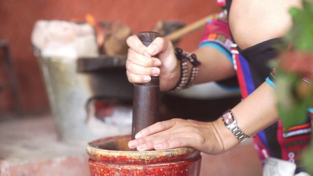 妇女用手捣碎和研磨混合香料和药草原料，用木臼视频素材