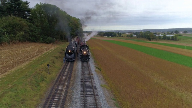 两辆蒸汽机车在雨天并排向上行驶的高空图视频下载