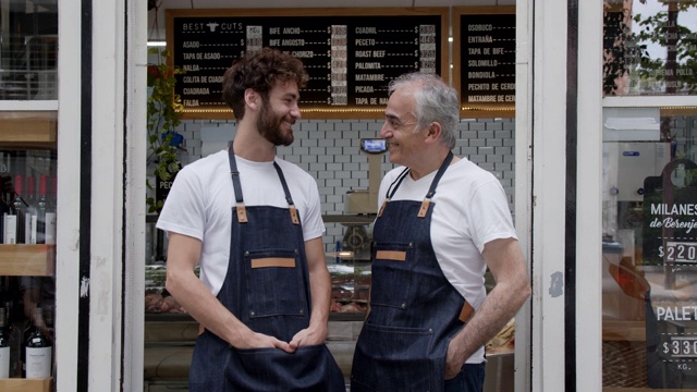 快乐的父亲和儿子的老板肉店看着对方微笑和交谈在入口处的业务视频素材