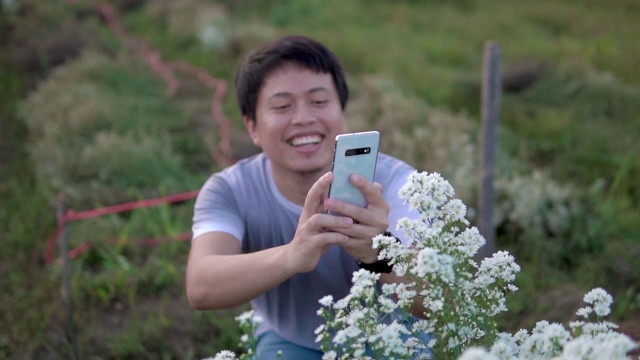 亚洲男人用他的智能手机拍摄花。视频下载