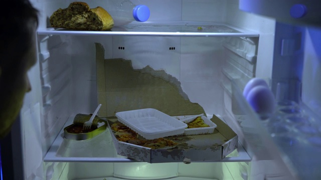 在冰箱里找食物的人。没刮胡子的男人挖冰箱，拿披萨。视频下载