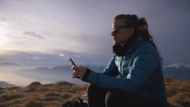 女性徒步旅行者在山顶使用智能手机视频素材
