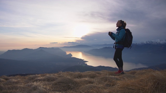 女性站在山顶拍摄日落视频素材