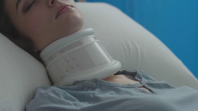 受伤的妇女躺在医院的病床上，颈圈和静脉注射视频素材