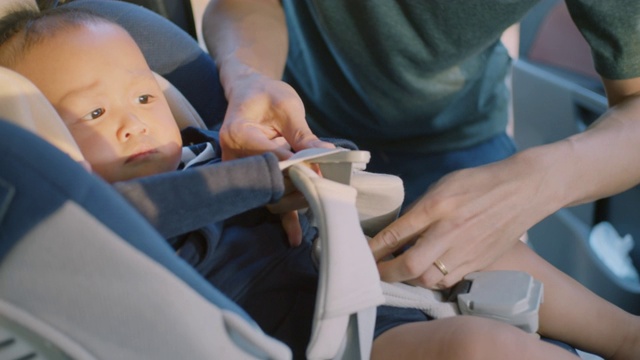 亚洲父亲把儿子放在汽车座椅上的特写，慢镜头视频素材