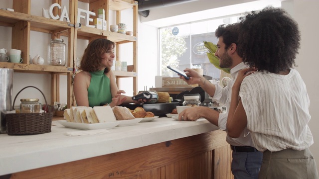 一个年轻的成年人在café用手机付款的慢动作视频视频下载