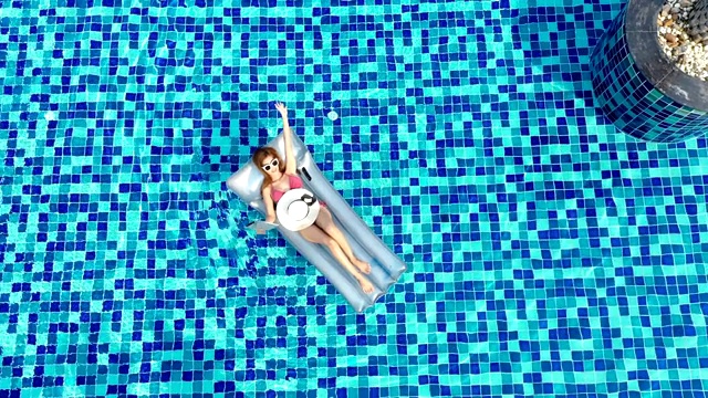 无人机鸟瞰图上的妇女漂浮在蓝色游泳池享受度假热带目的地。假期的概念视频素材