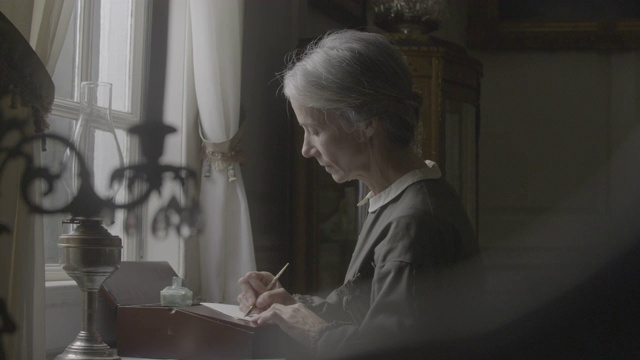 机架聚焦拍摄从一个年长的妇女书写与一个女性的形象烛台视频下载