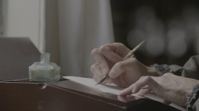 架对焦镜头从一个煤油灯到一个老年妇女的手写一个浸渍笔视频下载
